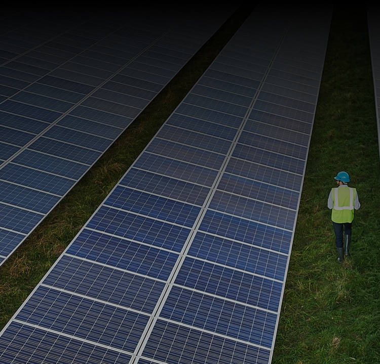 Safety worker in field of solar energy farm surrounded by solar panels